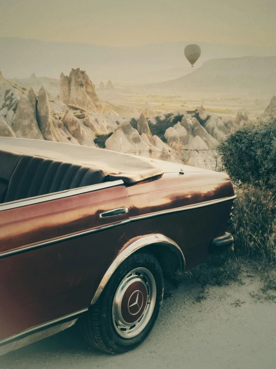 a small vintage car sitting in the middle of the desert