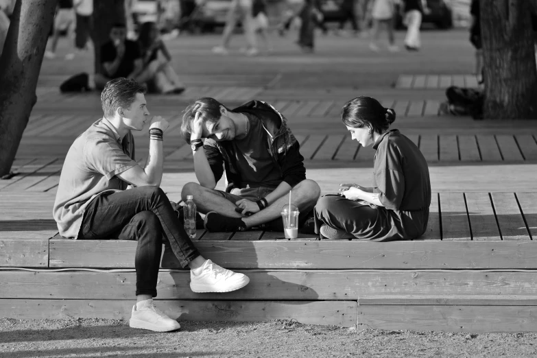 three people are sitting on a small step and one is reading a book