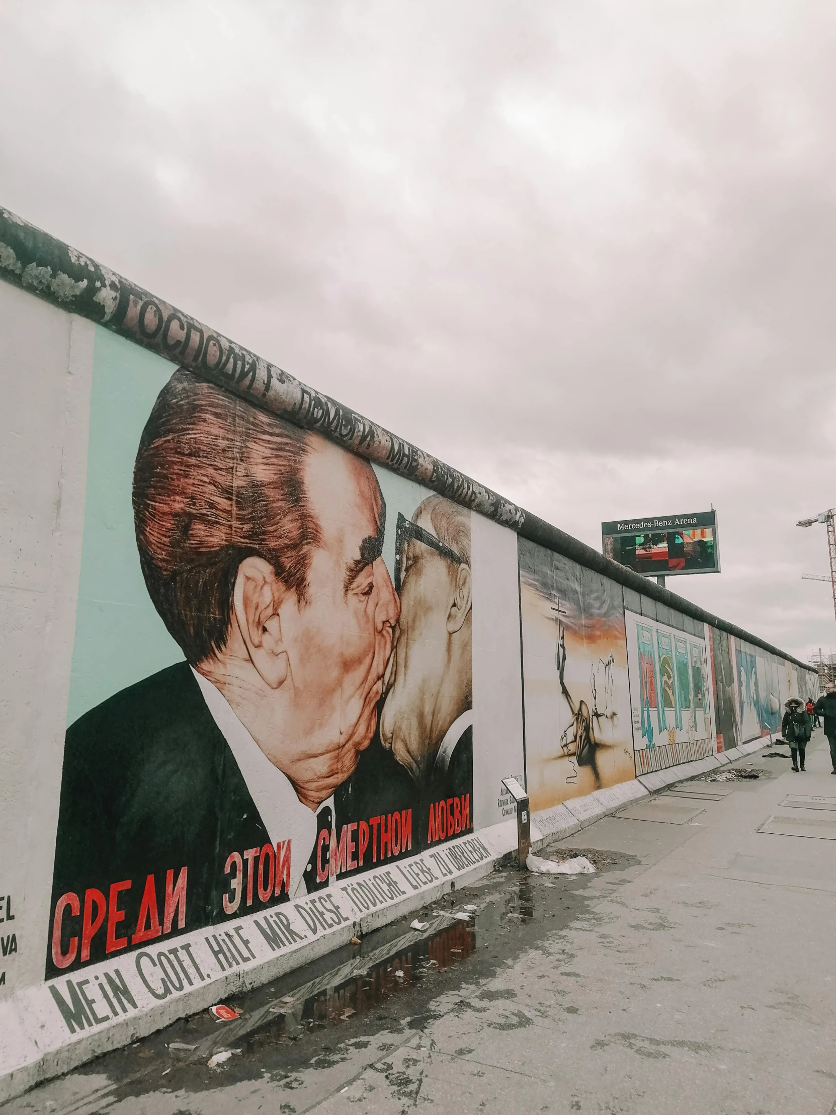 people are walking in front of a wall that has political pictures painted on it