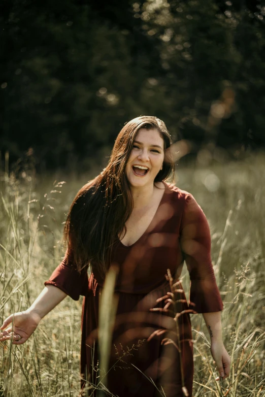 a woman is walking through the grass with her hand in her mouth