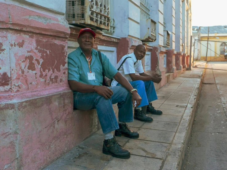 two men sitting down on the side of the road