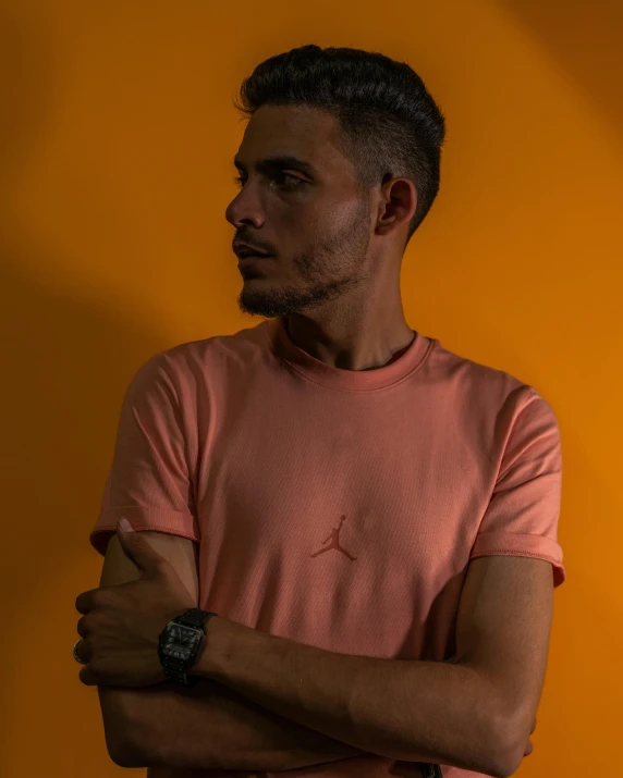 a man in pink shirt standing with arms folded