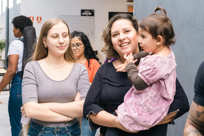 a woman holding a baby while standing between two other women