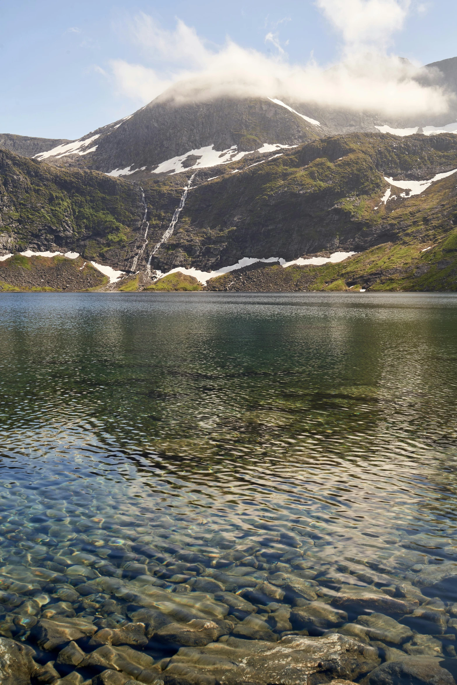 view from a small lake in front of snowy mountains