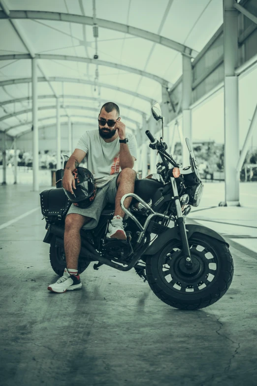 the man sits on his black motorcycle and gives a peace sign