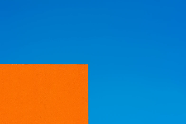 the corner of an orange building with a blue sky in the background