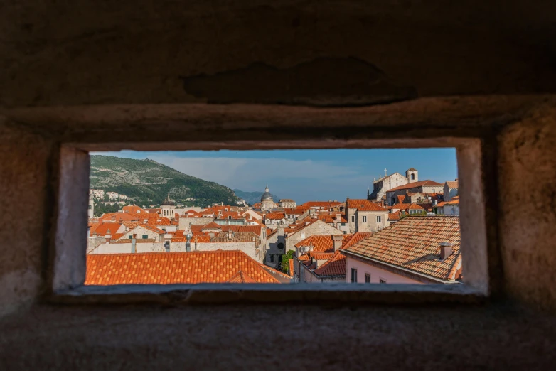 a view of some roofs and mountains from within a window