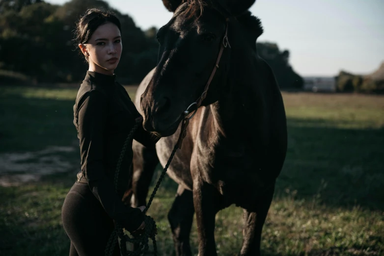 a woman standing next to a horse in a field