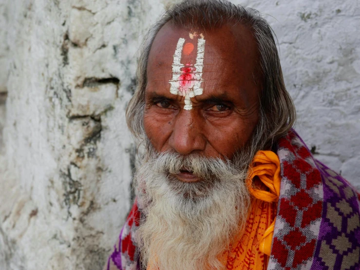 an old man with a red and white head piece in his eyes