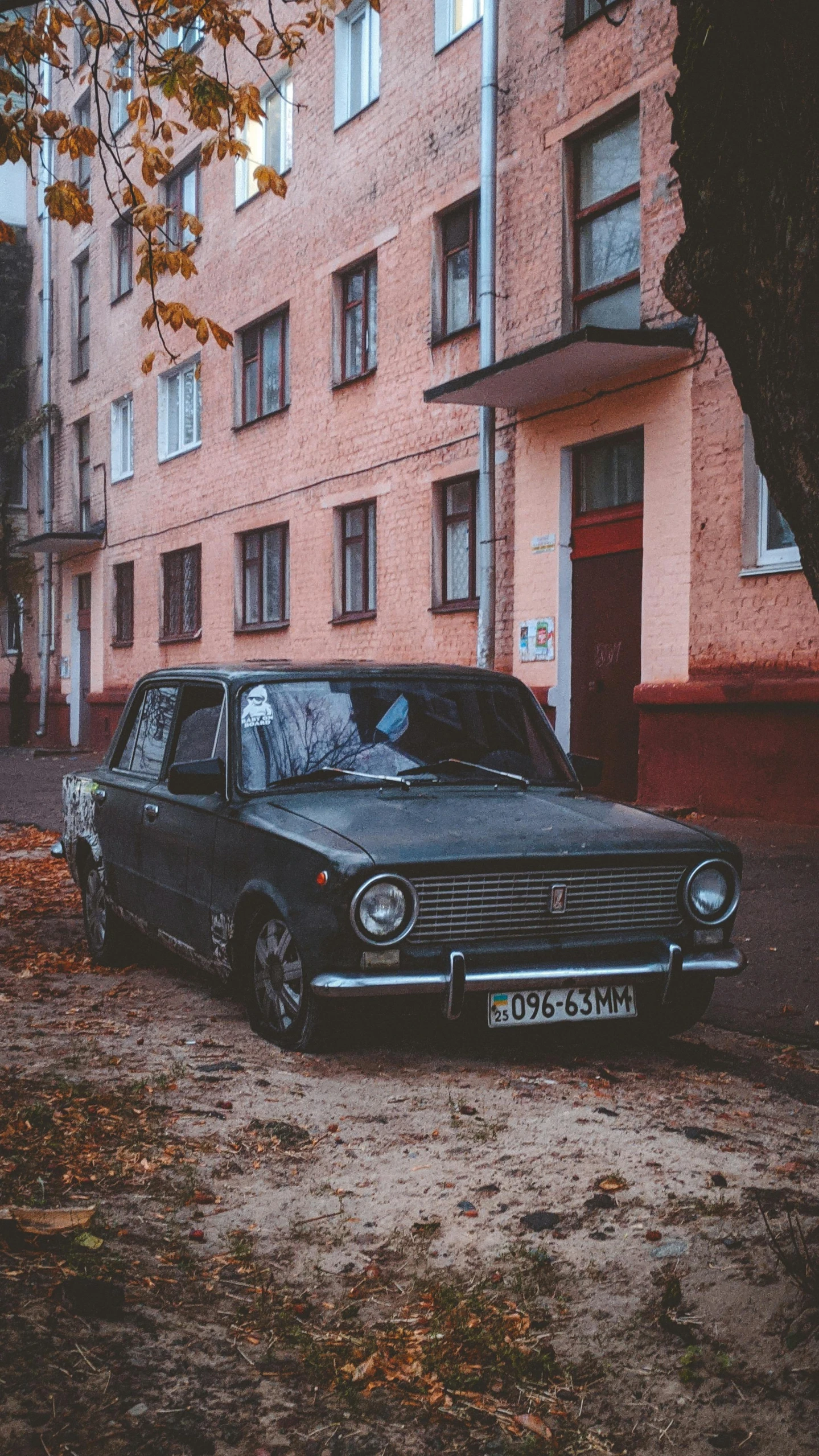 a black car sits outside a tall brick building