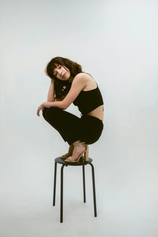 a beautiful woman sitting on a stool in the corner