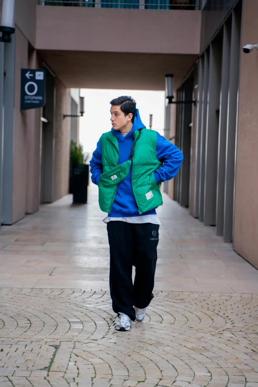 a man in blue and green jacket standing in front of a doorway