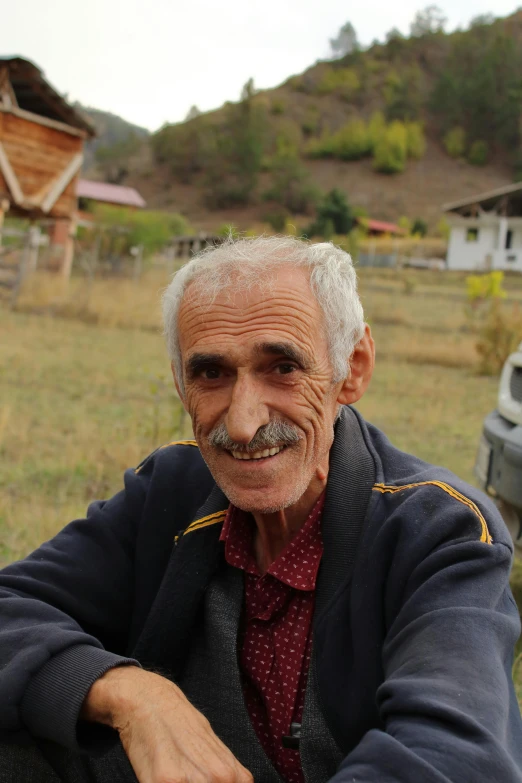 a man in a jacket sits with his arms crossed