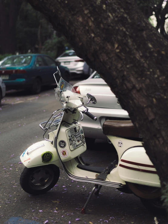 a white scooter is parked near many cars