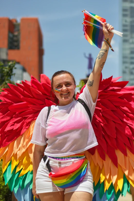 a woman with her arm in the air holds up a red and yellow kite with multiple colors