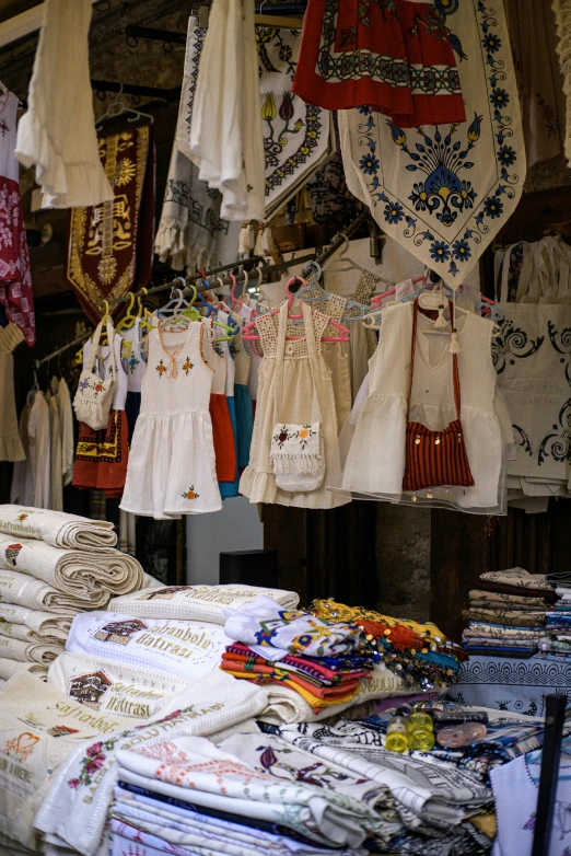 several colorful shirts hanging on poles outside a shop