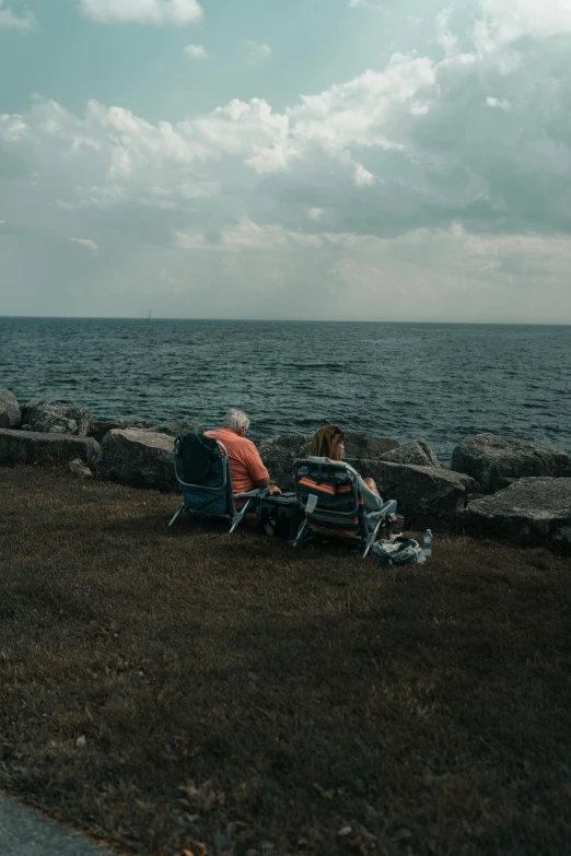 two people sitting on a bench by the water