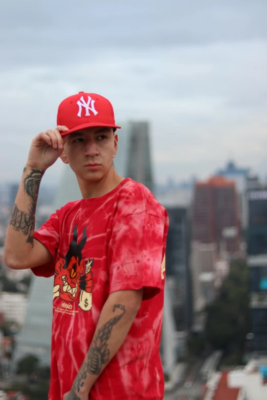 a man in a red shirt and red cap is holding his hair to the side