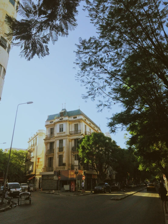 an old city building surrounded by a tree lined street