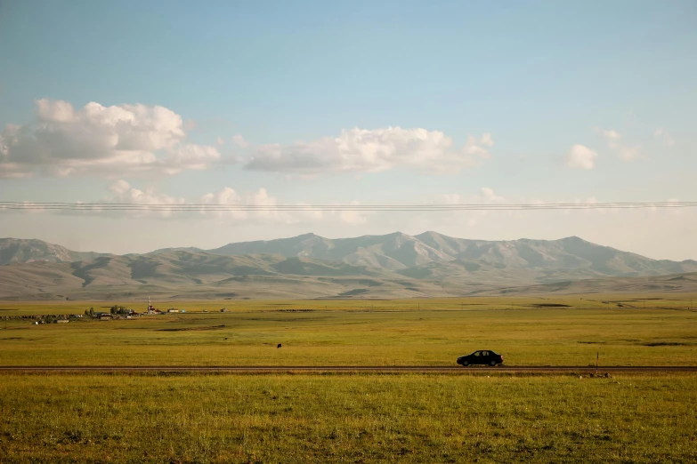 a green field of grass with a bunch of hills in the distance