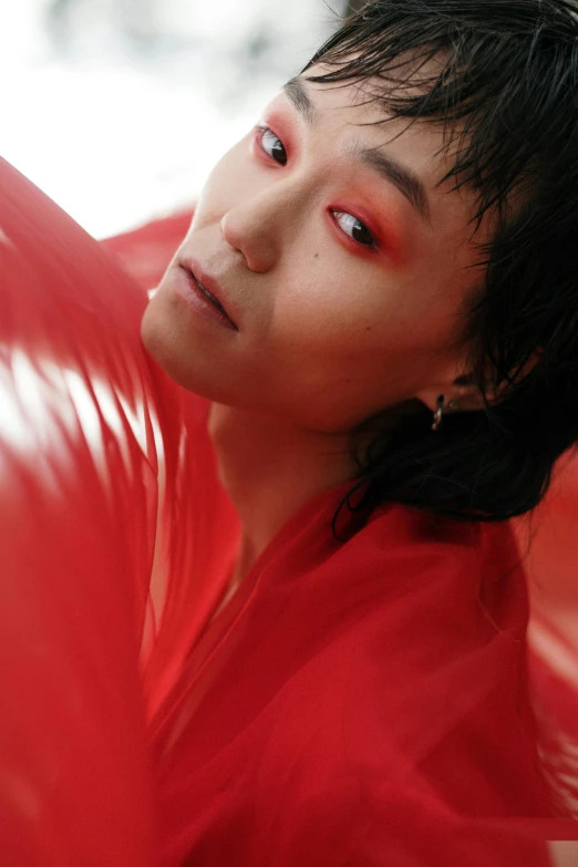 a young man with a bright red shirt, black hair and piercings