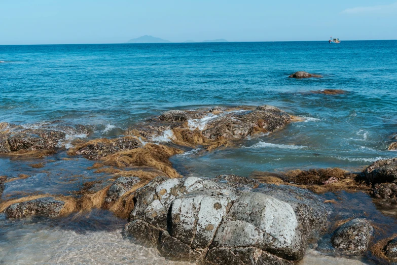 rocks in the water with small boats floating behind