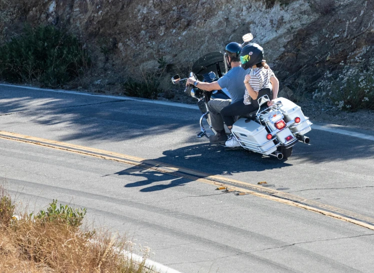 two people on motorcycles drive down the road