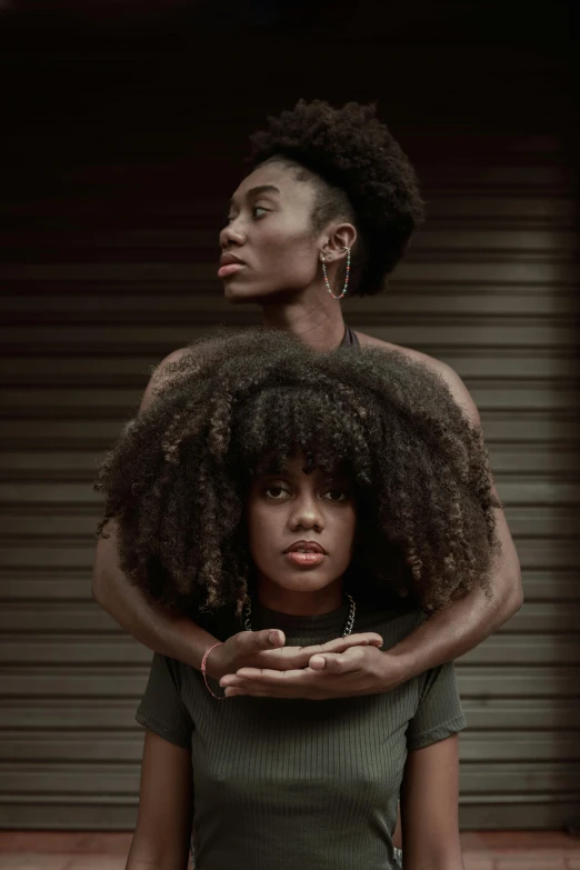 a woman with an afro holds her head while another stands behind her