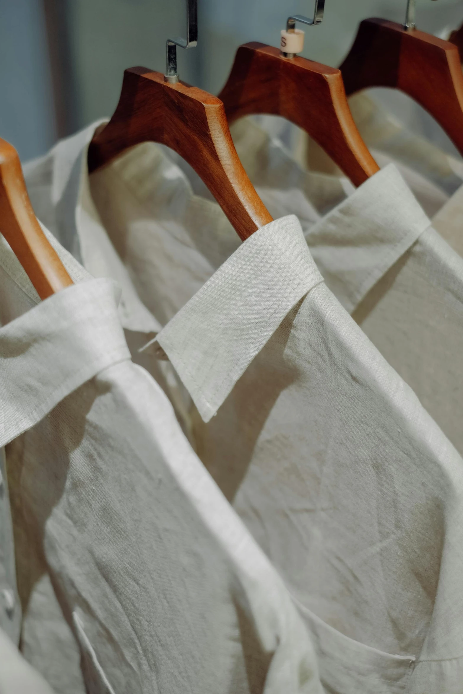 three wooden hangers with shirts on them on a rack