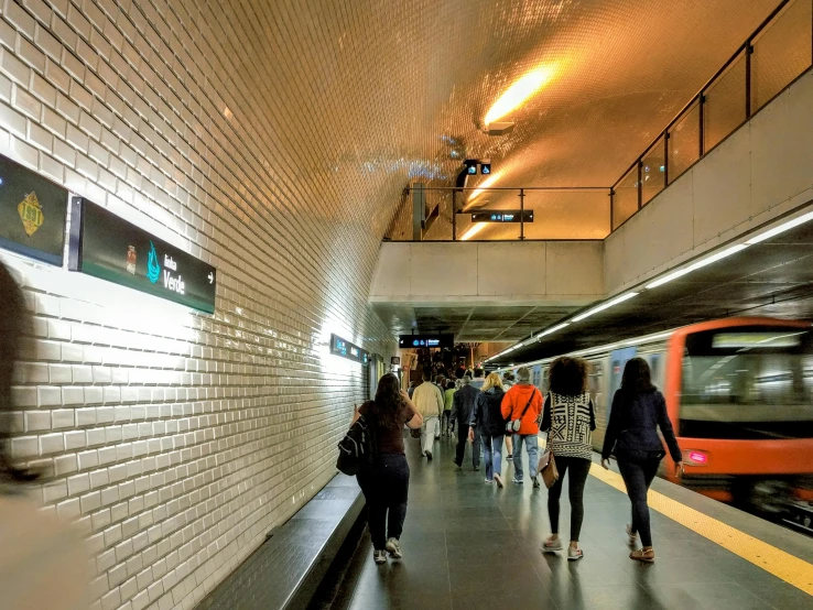 several people standing outside a building waiting for the subway to arrive