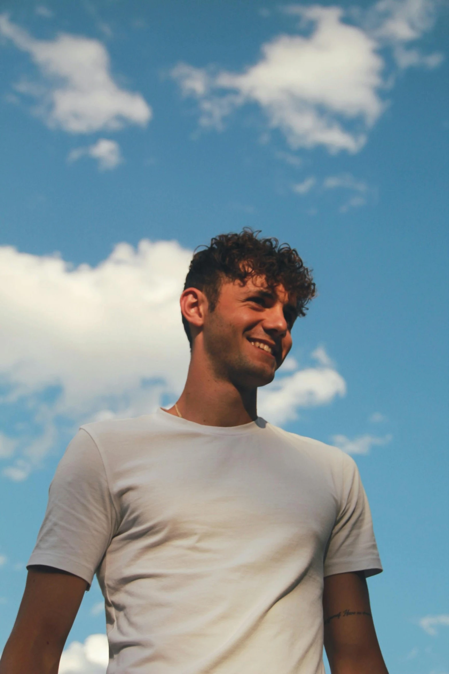 a man is smiling in front of a sky background