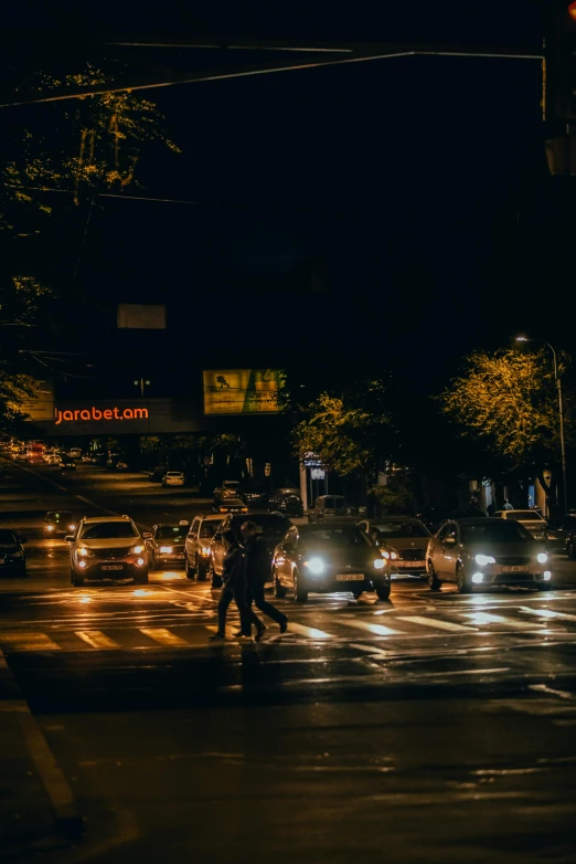 cars and pedestrians driving on a busy street at night