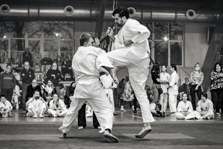 two people standing in front of a crowd doing karate