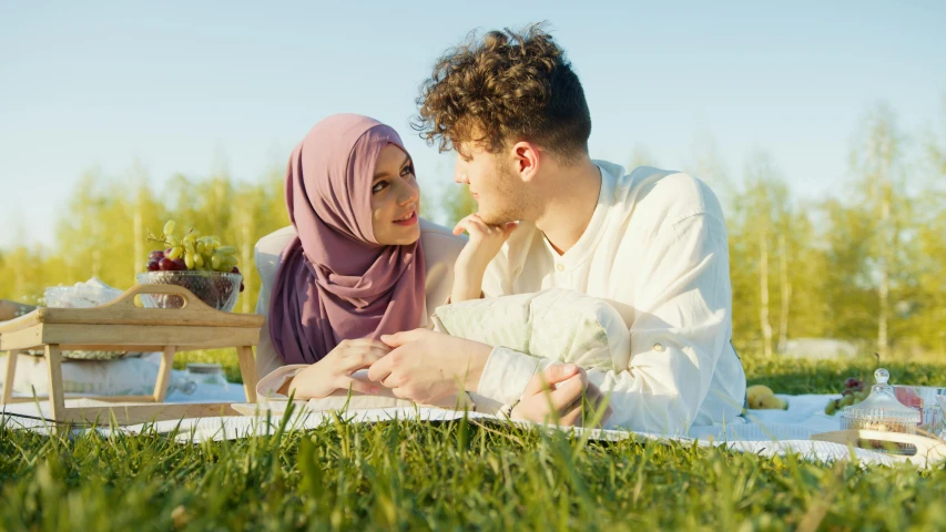 a beautiful woman sitting next to a man in a white shirt