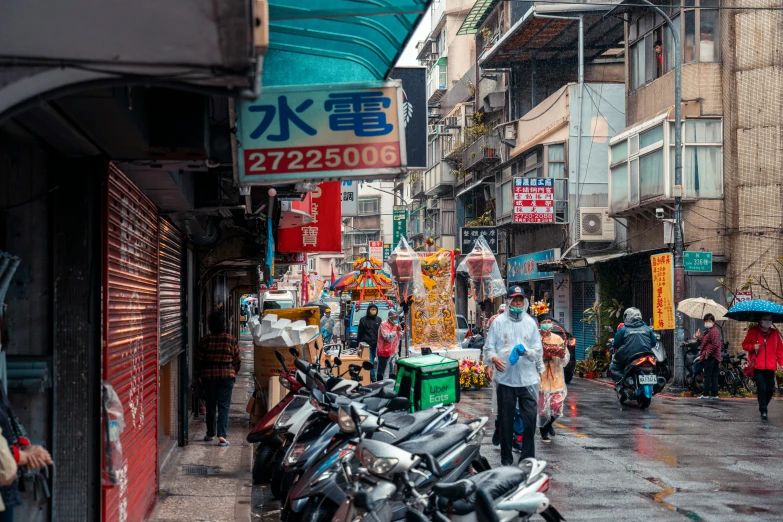 a wet street with lots of people and motor scooters