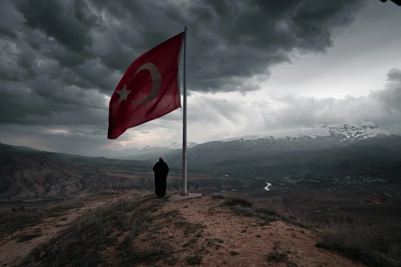 a person is standing on top of a hill with a flag