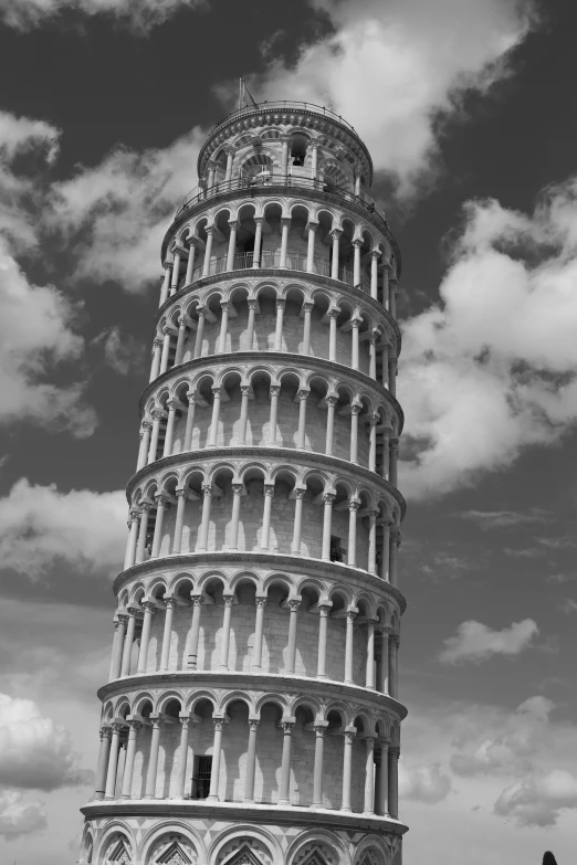 a large leaning tower next to a cloudy sky