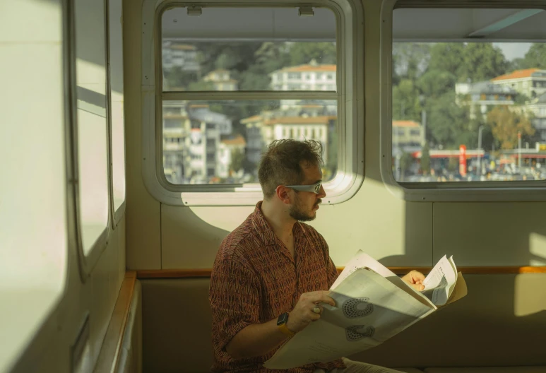 man reading on train in the sun