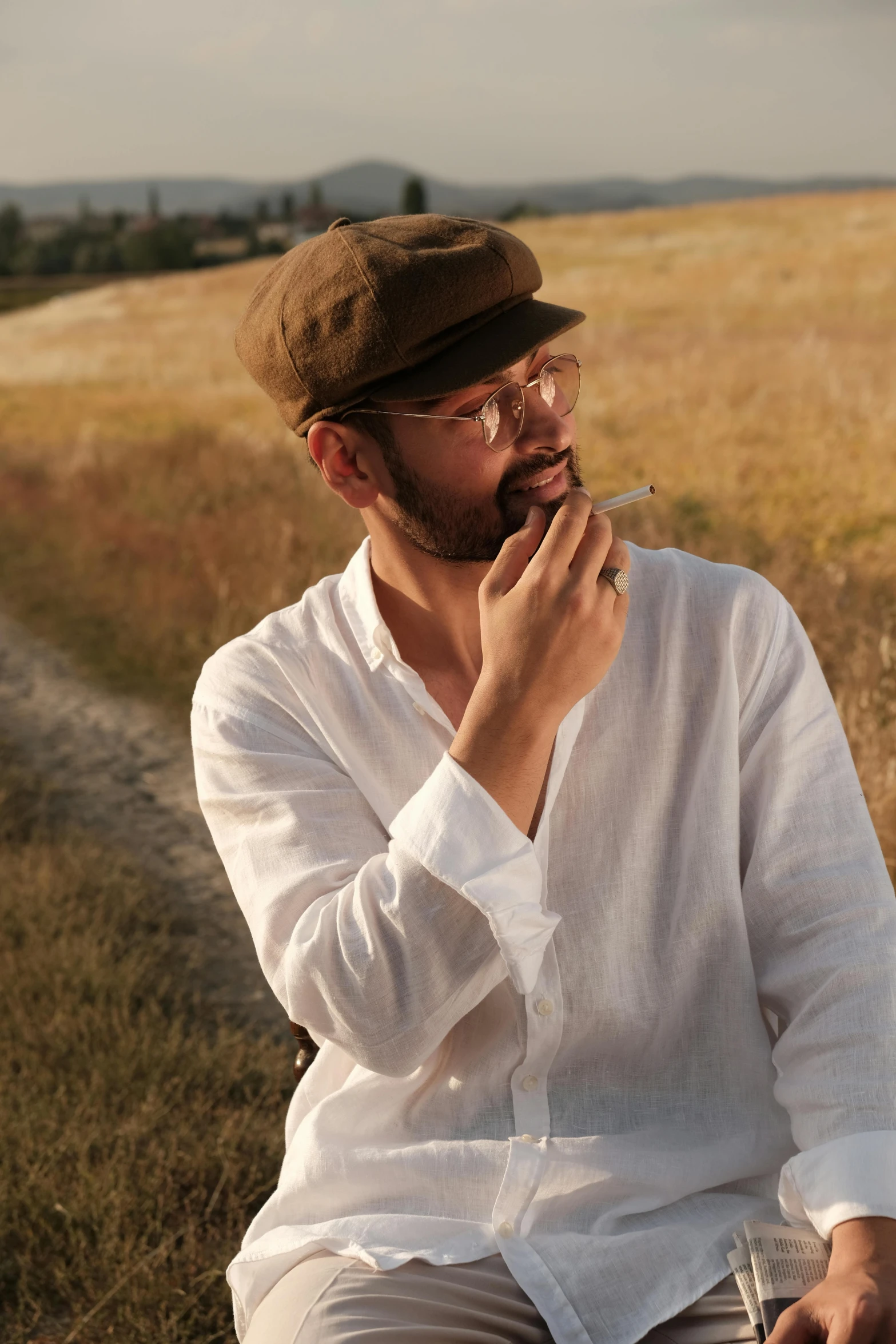 a man with glasses and beard sitting in a field