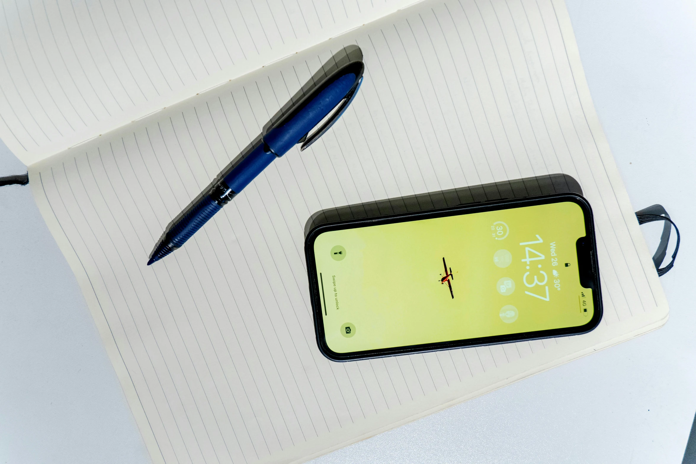 a pen, phone and a smart watch laying on a desk