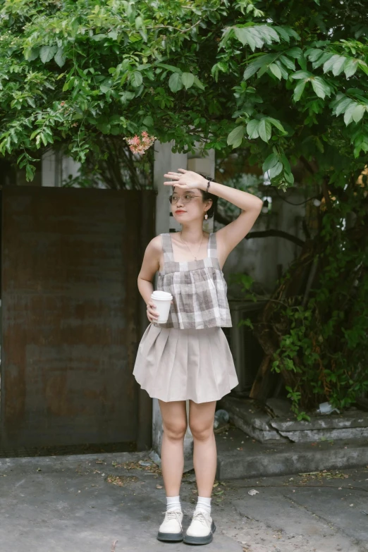 a woman in a plaid shirt and dress holding a cup of coffee