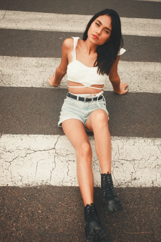 a girl in denim shorts, crop top and black boots