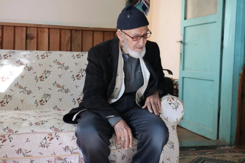 an older gentleman is sitting on a couch