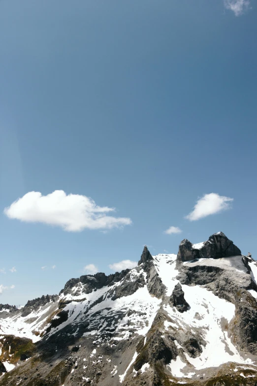 a mountain with snow on it and a few clouds