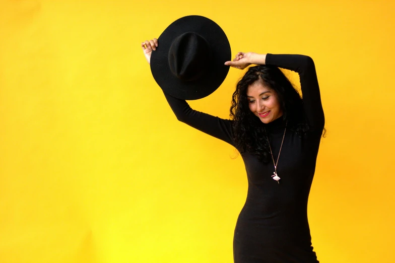 the beautiful woman is holding her hat and posing for a picture