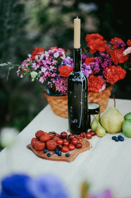 a table with flowers, fruits and a bottle