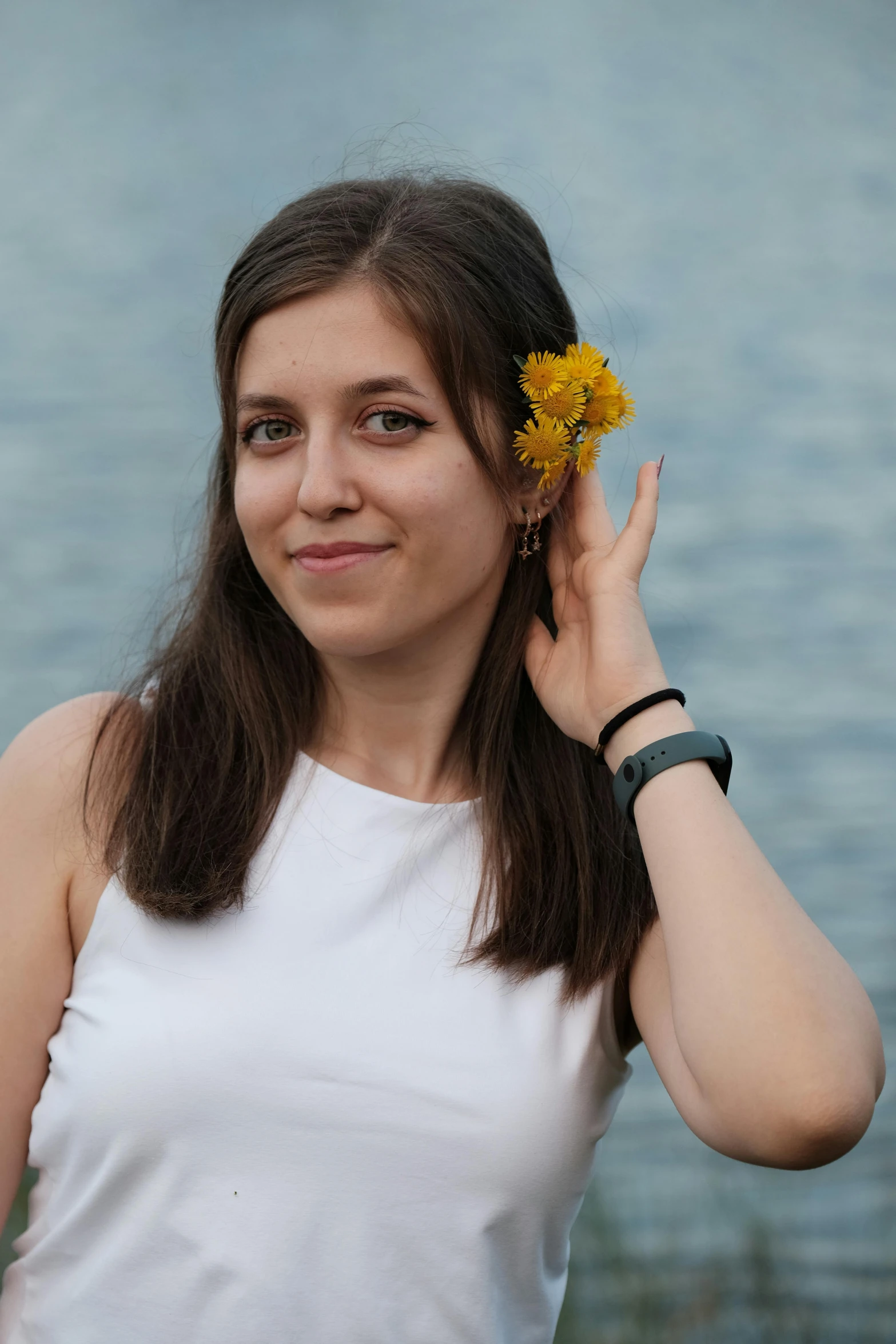 a young lady holding a yellow flower up to her ear