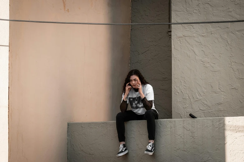 woman sitting on top of concrete bench and looking down at soing