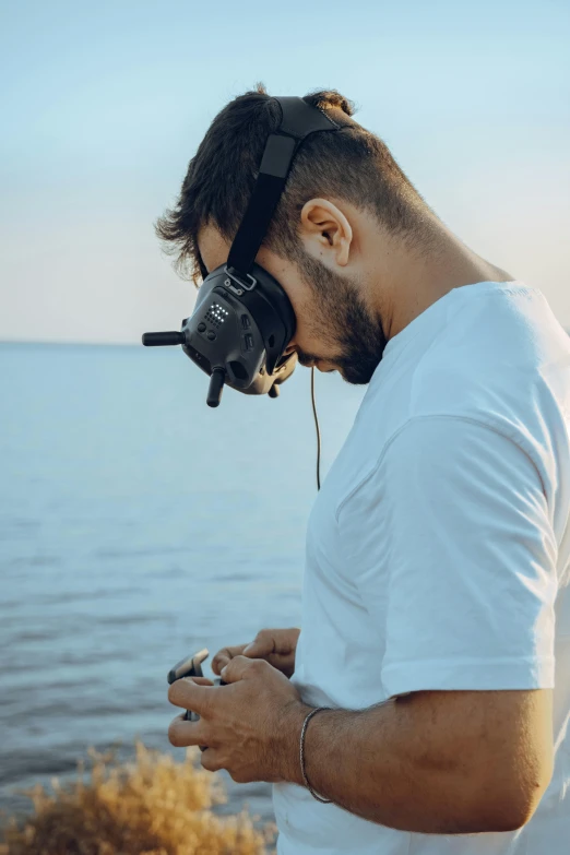 man wearing head phones standing on shore by the ocean