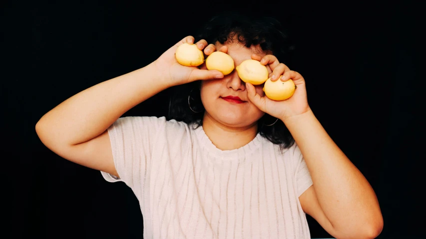 a person holds up some yellow donuts in front of her eye